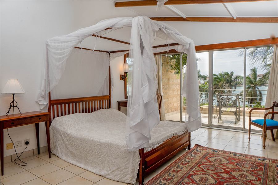 Bedroom with a four-poster bed, opening onto a balcony over the creek